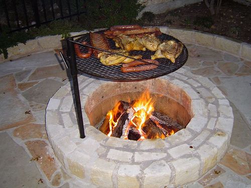 an outdoor fire pit with food cooking on it