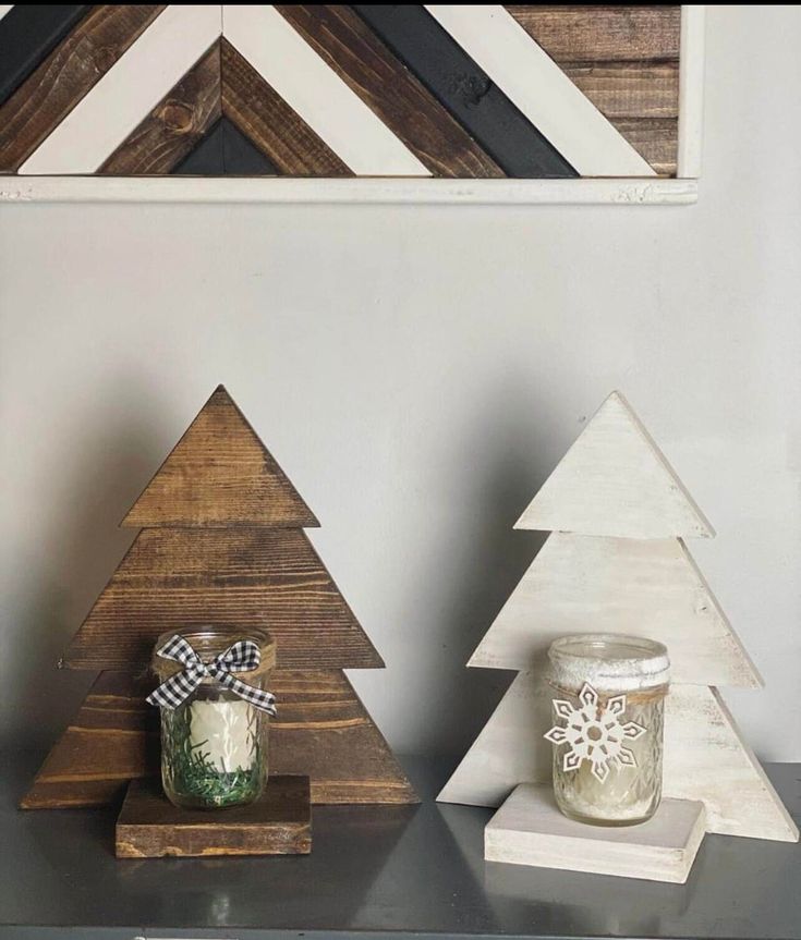 three wooden christmas trees on a shelf with a mason jar next to one and another