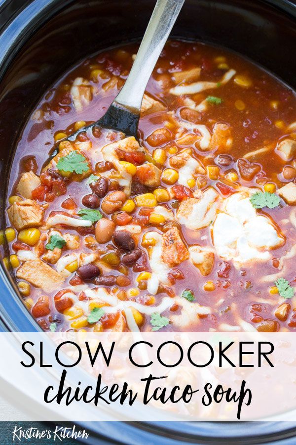 a crock pot filled with chicken, beans and tortilla soup next to a wooden spoon