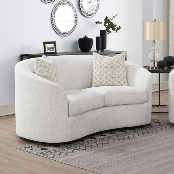 a living room with two white couches and mirrors on the wall above them,