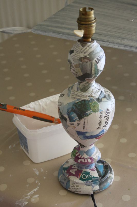 a lamp made out of newspapers sitting on top of a table next to a container