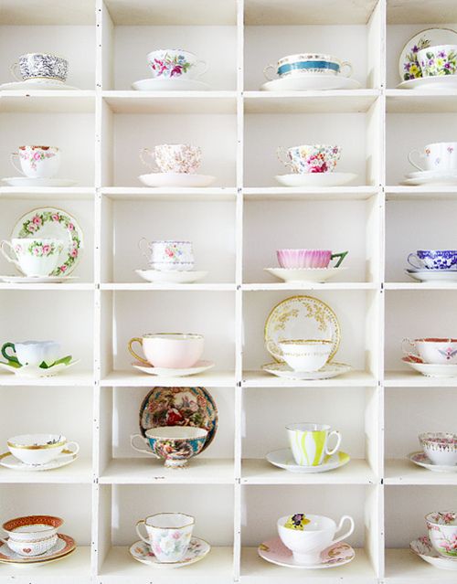 a white shelf filled with lots of cups and saucers