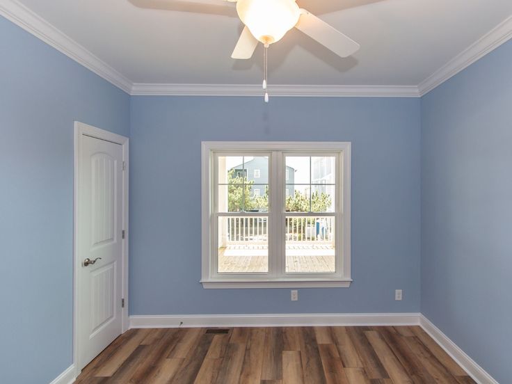 an empty room with blue walls and white trim on the ceiling, wood flooring