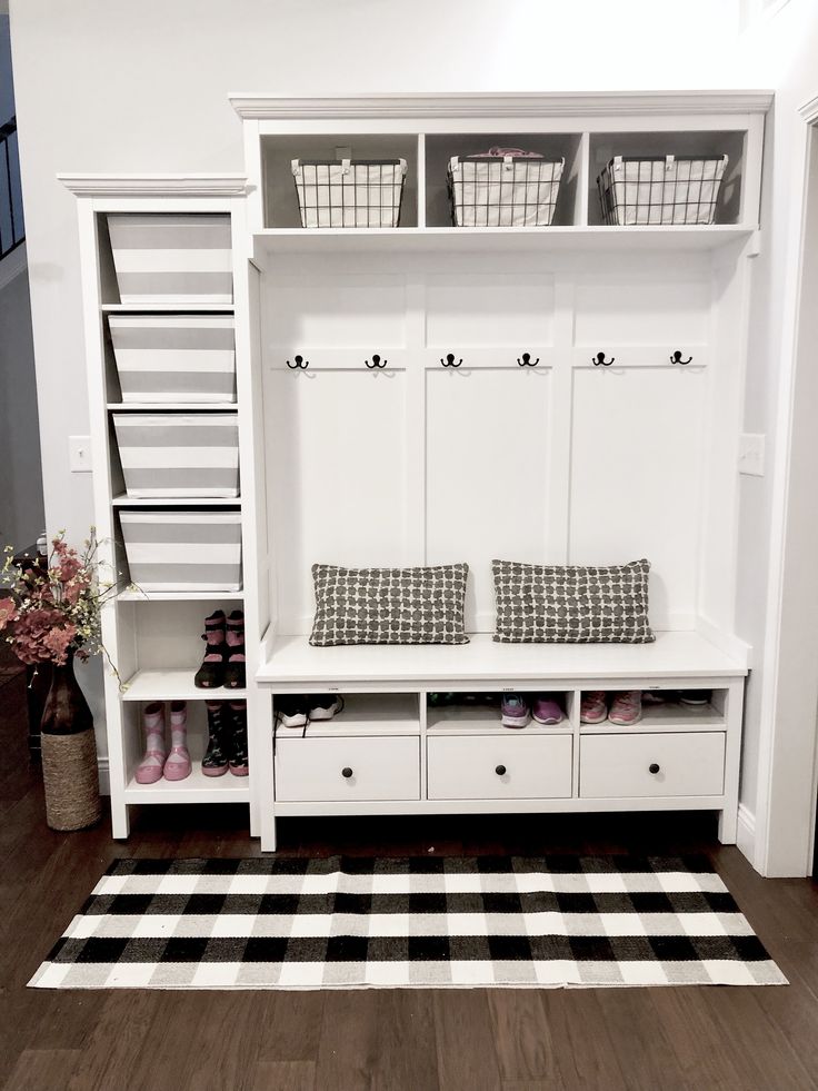 a white bench with two baskets on top of it next to a black and white checkered rug