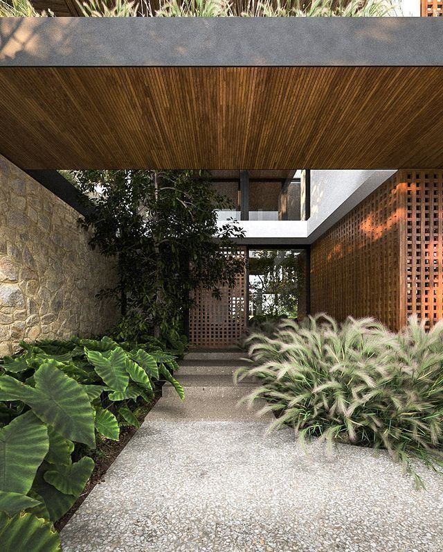 the walkway is lined with green plants and rocks, leading to an open air space