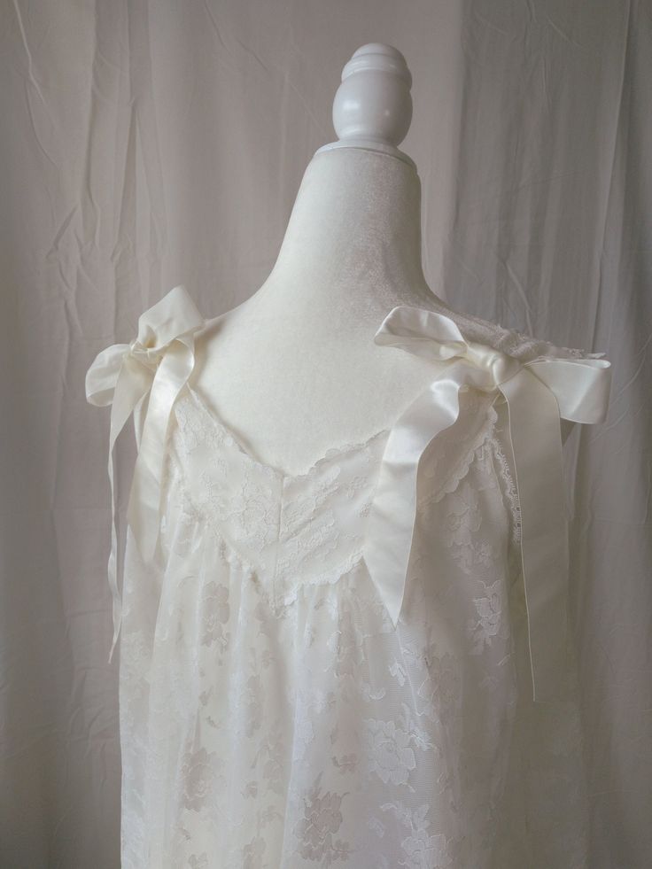 Vintage white lace and ribbon nightgown by Aristocraft. Features sheer lace overlay against nylon lining, standard sleeveless straps decorated with satin bows on the back of the straps, decorative satin ribbon accents placed vertically across the front, and satin bows across the lightly ruffled hem. Straps are not adjustable. Era: Circa 1960s Condition: Excellent Size: Small Color: White Brand: Aristocraft Measurements: 20.5in pit to pit, 38.5in length Fabric Content: 100% nylon Shown on a mannequin with a 33" bust, 26" waist, and 35" hips. Fits a size 2-4. Model is 5'5 with a 34A bust. Some garments may be clipped onto mannequin or model for display. MORE INFO: *Please, note that these items are vintage. Therefore, it is expected to find some wear. Ariessence by Ariel is an admirer of fas Wedding Coquette, White Coquette, Lingerie Babydoll, Big Tshirt, Old Hollywood Glam, Vintage Nightgown, Hollywood Glam, Babydoll Lingerie, White Brand