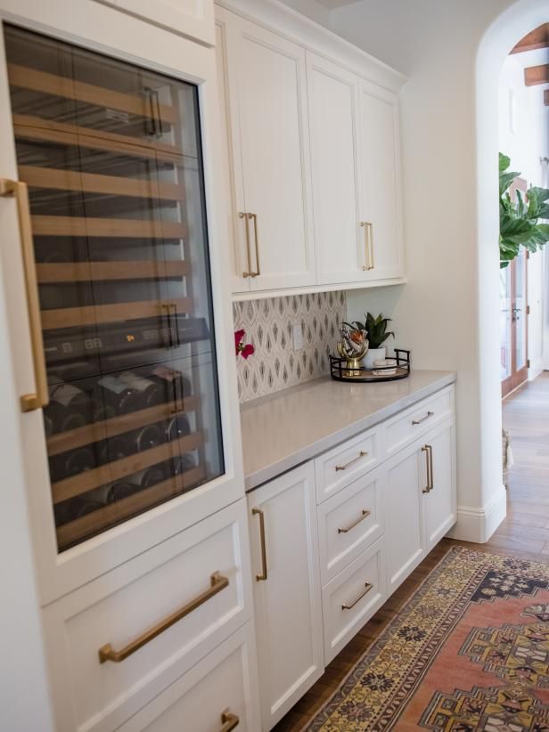 a kitchen with white cabinets and gold handles