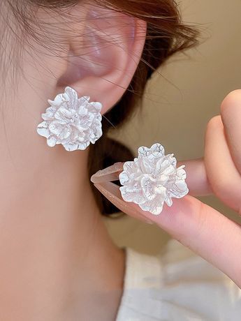 a close up of a person's ear wearing earrings with flowers on the side