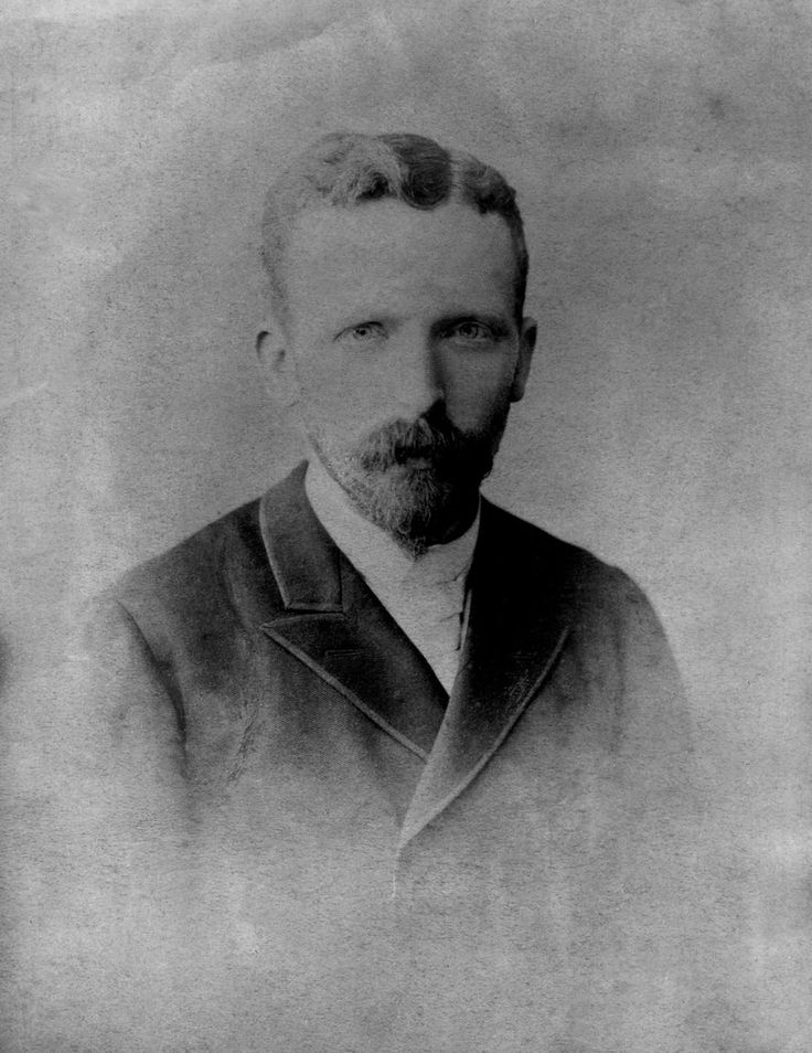 an old black and white photo of a man with a beard wearing a suit jacket