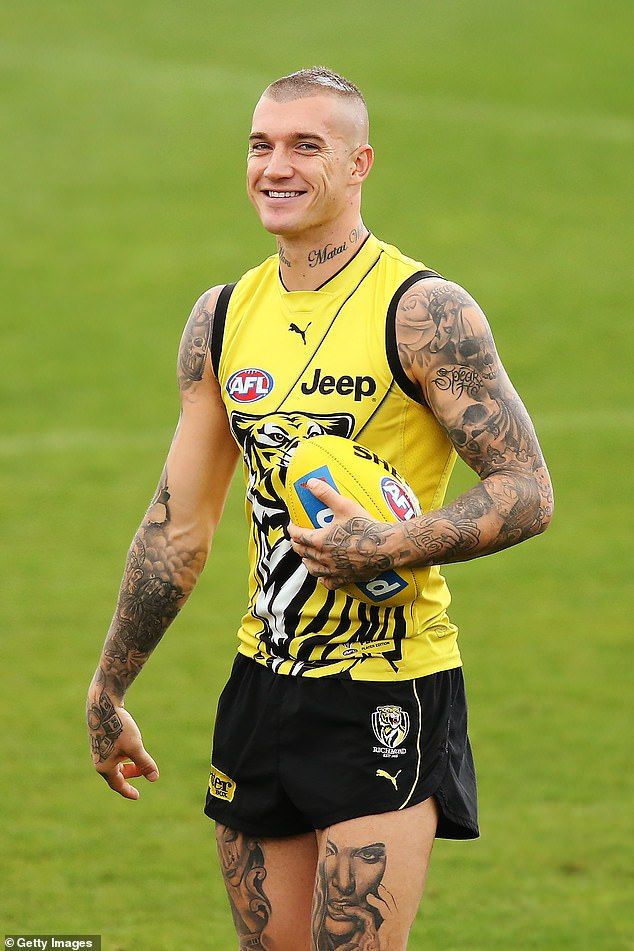 a man with tattoos on his arm and chest holding a ball in front of him