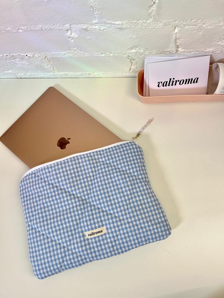 an apple laptop computer sitting on top of a white table next to a cup and pen holder