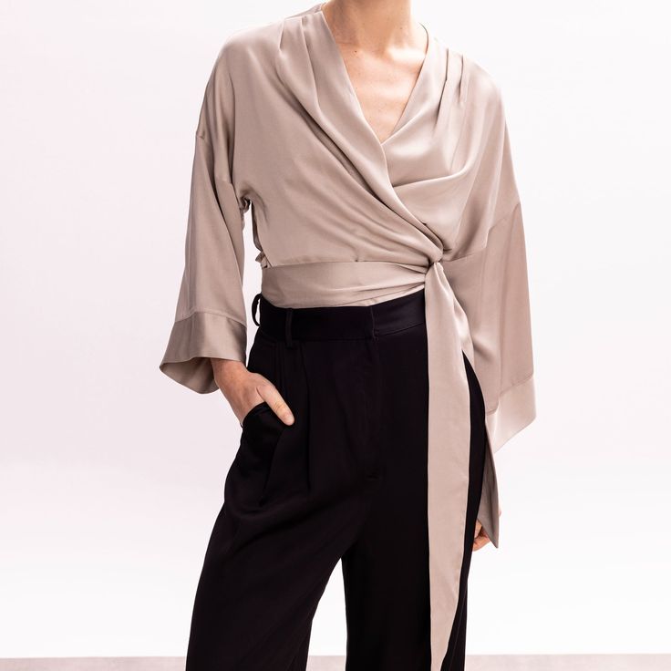 Easy and versatile, this blouse is crafted from high quality viscose fabric and has wide kimono sleeves. It is designed to wrap & tie in different ways. Wrap it around the waist and tie the straps at the front side, for a more classic look. Or cross the straps in the middle front (semi-tie, braided) and then wrap them around the waist and tie them either on the back or the front.  Pair it with its coordinating bias-cut skirt from the collection.   All pieces are cut one by one for an impeccable Silk Wrap Blouse For Evening, Silk Evening Wrap Blouse, Versatile Viscose Blouse For Evening, Silk Top With Draped Sleeves For Work, Silk Tops With Draped Sleeves For Work, Chic Wrap Blouse With Tie Sleeves, Chic Silk Wrap Blouse, Spring Season Formal Wrap Blouse, Elegant Workwear Wrap Top With Tie Waist