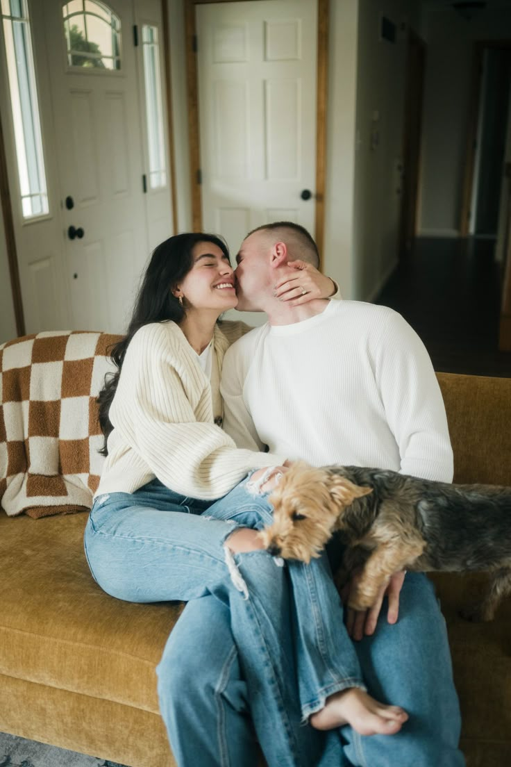 a man and woman sitting on a couch with a dog