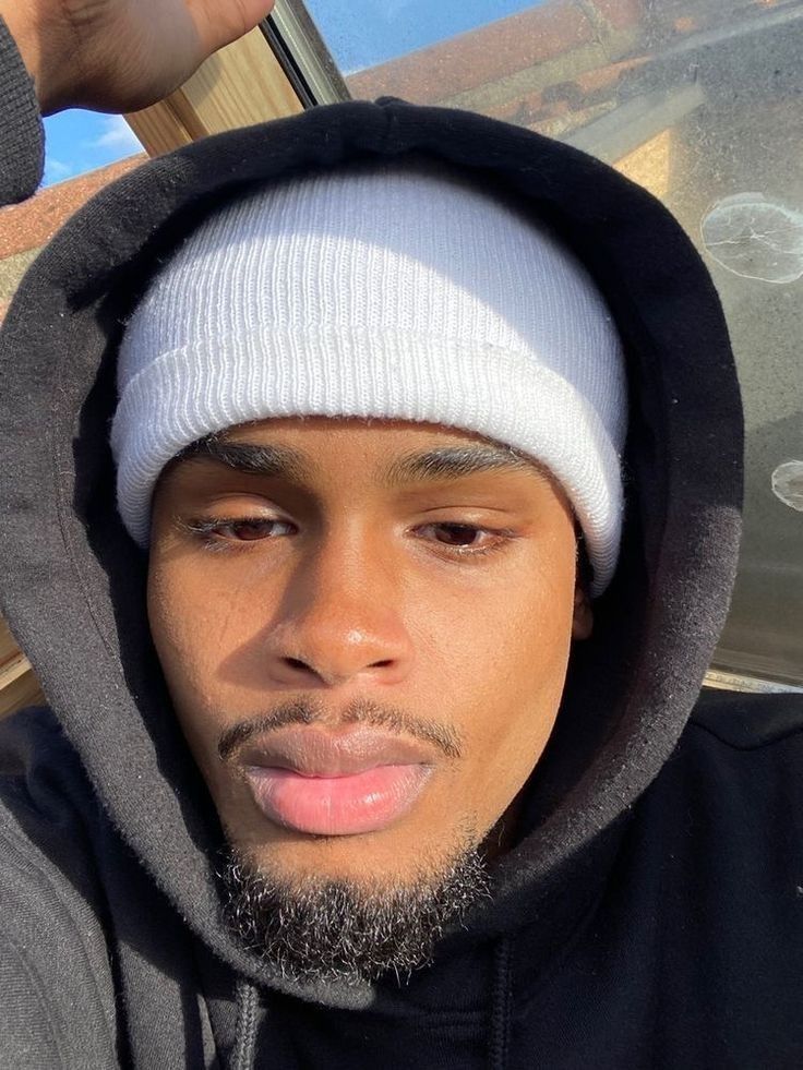 a young man wearing a white and black hoodie is taking a selfie with his cell phone