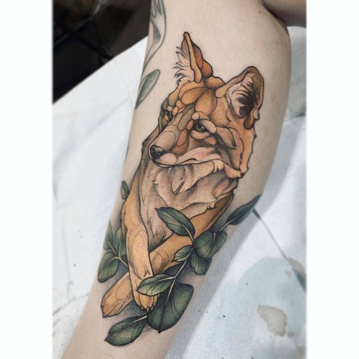 a woman's arm with a tattoo of a fox and leaves on the side