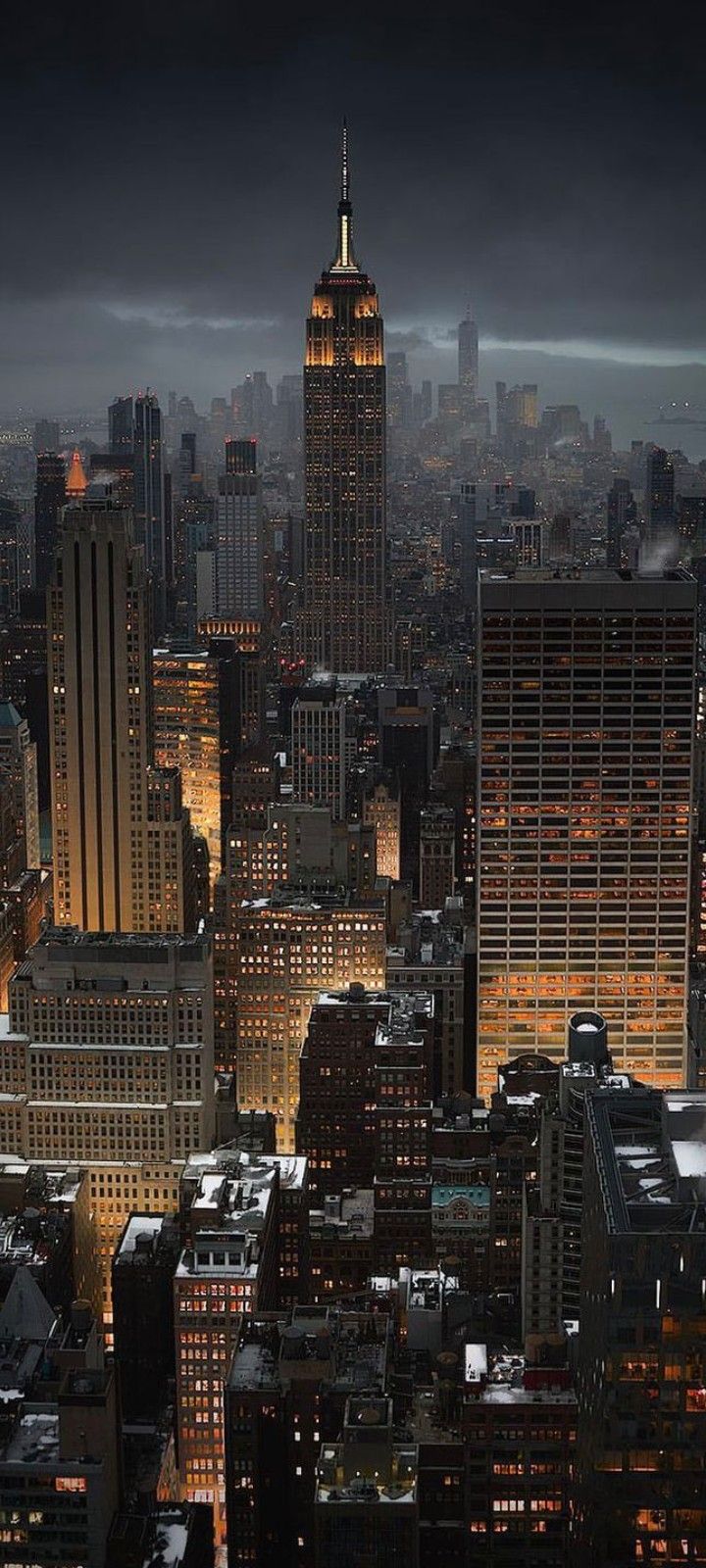 an aerial view of the city at night with skyscrapers lit up and dark clouds in the sky