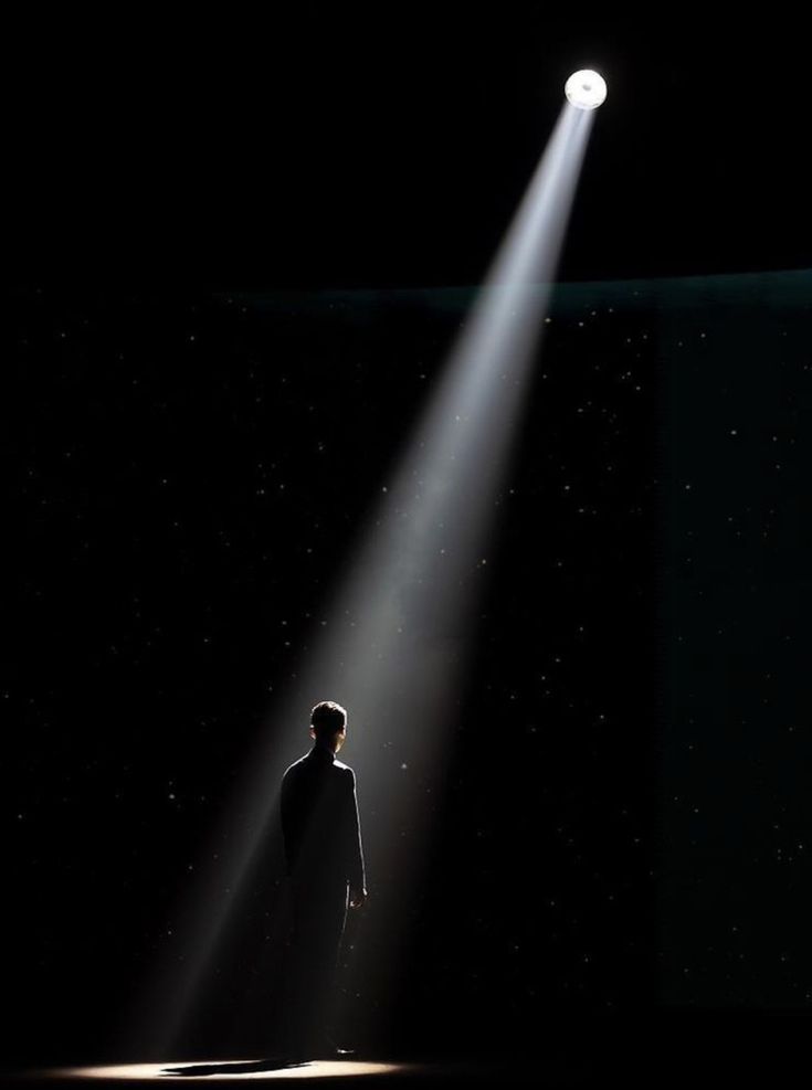 a man standing under a spotlight in the dark