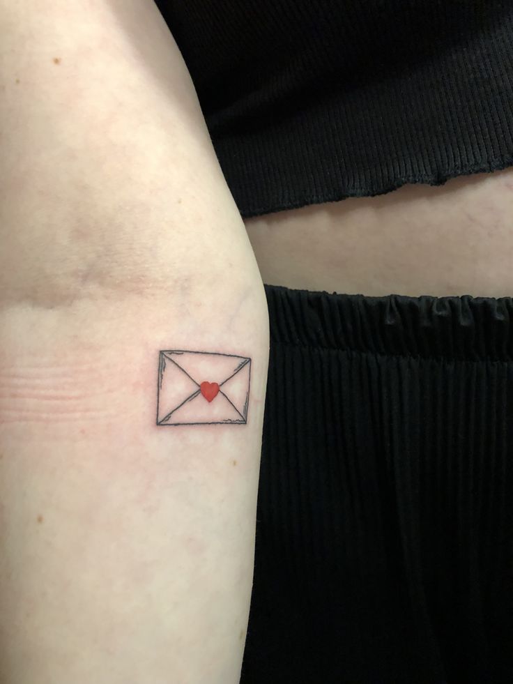 a woman's arm with a small envelope tattoo on the left side of her right arm