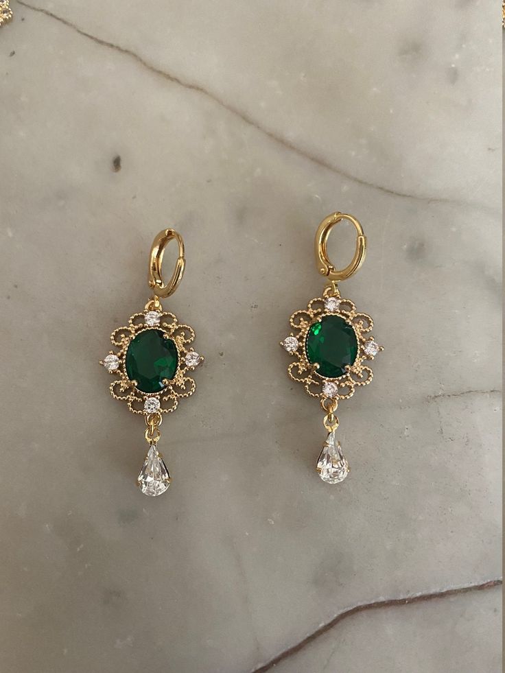 Ornate gold-plated drop earrings measuring 3.8 cm x 1.6 cm with an oval emerald green jewel and crystals. Hung on high quality gold-plated ear wires. Also available with gold-plated huggie hoop earrings measuring 1.2 cm x 1.4 cm. Nickel Free. Comes in a pair and the base metal is brass. INTERNATIONAL BUYERS please choose the tracking option if you would like your order to be tracked. FREE tracking upgrade with 3 items or more purchased. JEWELLERY CARE please don't wear plated jewellery in the sh Gold Plated Drop Earrings For May Birthstone, Gold Plated Earrings For May Birthstone, Gold Oval Crystal Earrings For Party, Gold Emerald Dangle Earrings, Gold Emerald Earrings For May Birthstone, Elegant Green 14k Gold Earrings, Elegant Gold Plated Green Hoop Earrings, 14k Gold Green Earrings, Green 14k Gold Filled Dangle Earrings