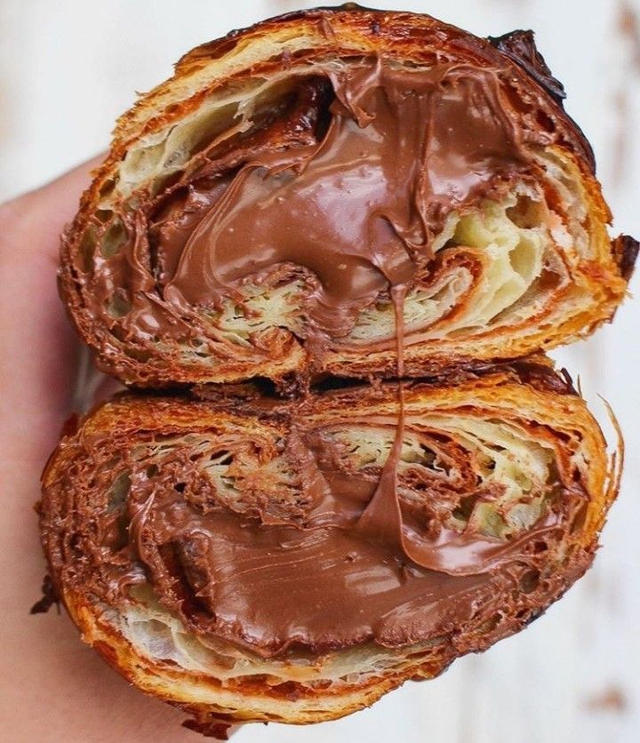 two pieces of bread with chocolate frosting on them in the palm of someone's hand