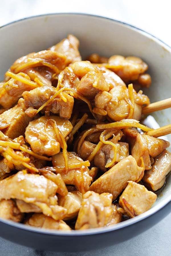 a bowl filled with chicken and chopsticks on top of a table