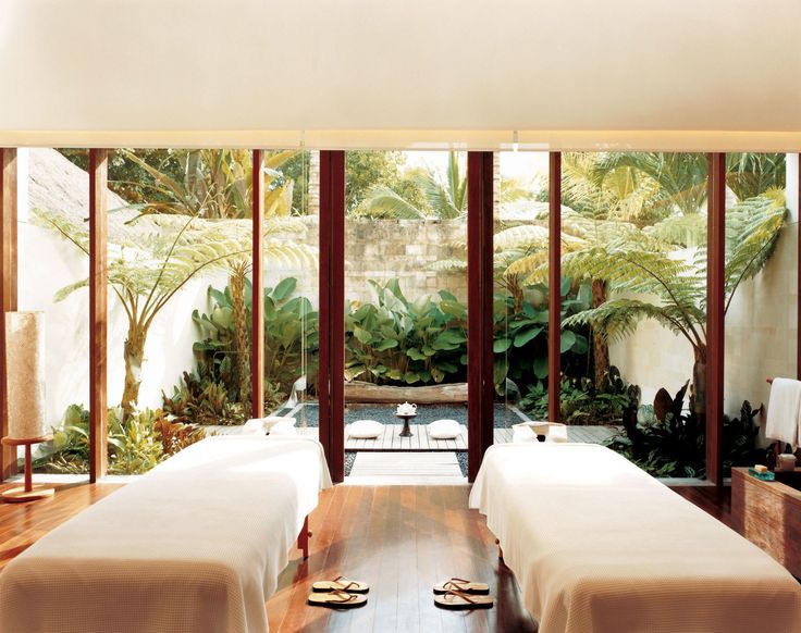 two beds in a room with wooden floors and large windows that look out onto the jungle