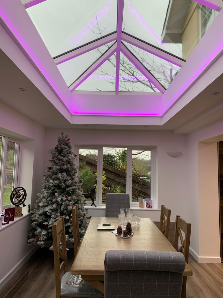 a dining room with a skylight and wooden table surrounded by christmas trees in the background