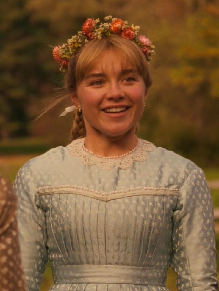 a woman in a blue dress standing next to another woman wearing a flowered headband