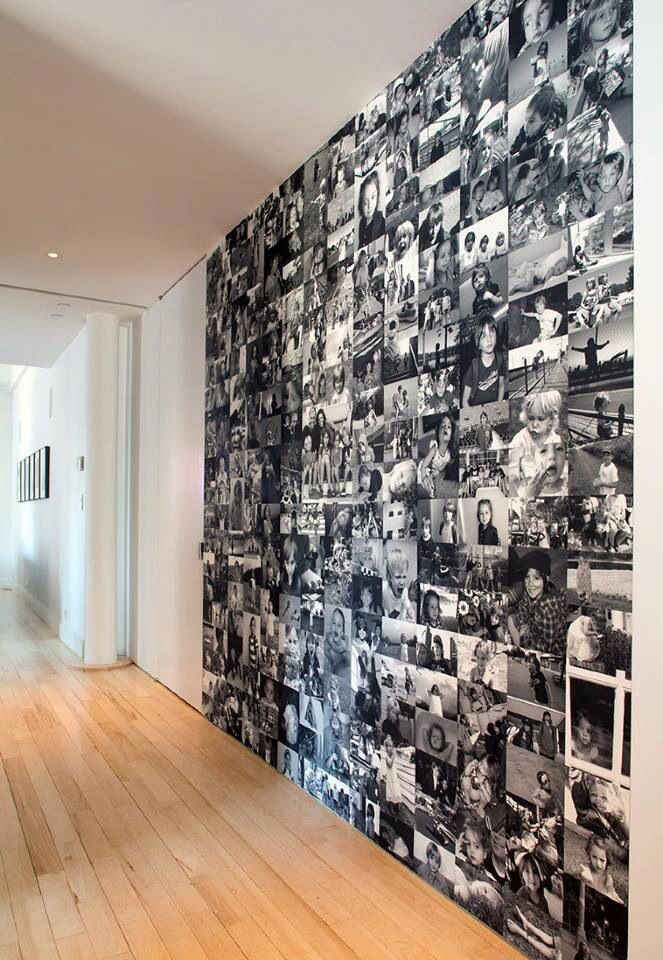 a wall covered in black and white photos next to a hallway with wooden flooring