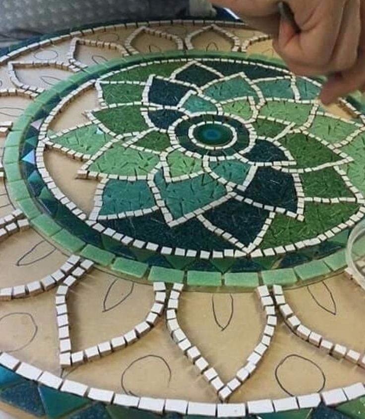 someone is working on a mosaic table top