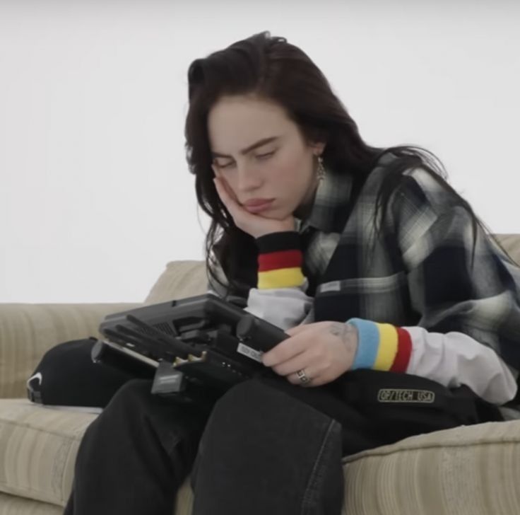 a woman sitting on top of a couch next to a remote control in her hand