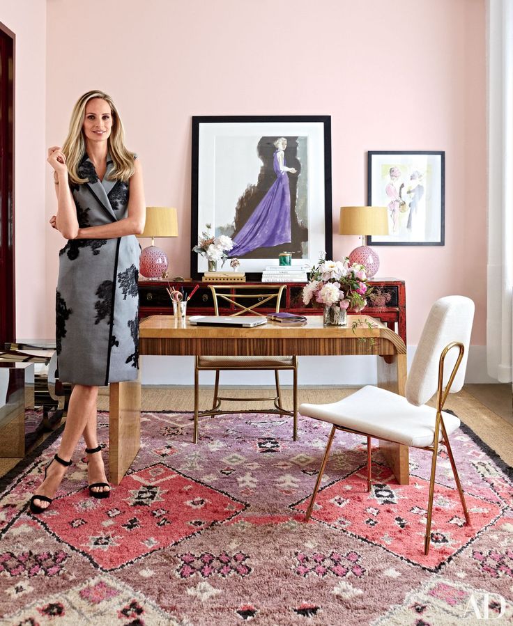 a woman standing in front of a desk with a chair and lamp on top of it