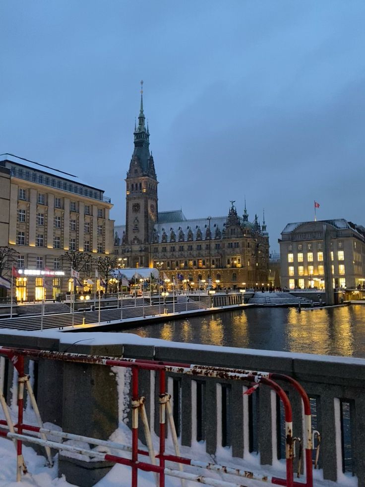 the city is lit up at night with snow on the ground and buildings in the background