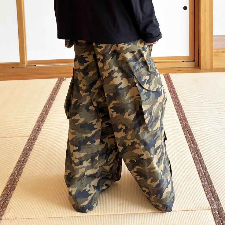 The Camo Wide-Leg Cargo Pants offer the perfect fusion of military-inspired style and casual comfort. Featuring an all-over classic camouflage print, these pants are designed for both functionality and fashion. With practical flap pockets sewn on the sides of the knees, near the hemline, and on the back, these cargos are as functional as they are stylish. Crafted from premium fabric, the oversized fit adds a modern, relaxed feel, making them an ideal choice for everyday wear. Classic camouflage Military Style Baggy Pants With Patch Pockets, Outdoor Camouflage Cargo Pants With Patch Pockets, Military Style Cargo Pants With Hip Pockets, Military Style Baggy Parachute Pants With Patch Pockets, Military Style Parachute Pants With Side Pockets, Camouflage Cotton Parachute Pants With Side Pockets, Cotton Camouflage Parachute Pants With Side Pockets, Military Parachute Pants With Cargo Pockets, Military Parachute Pants With Multiple Pockets