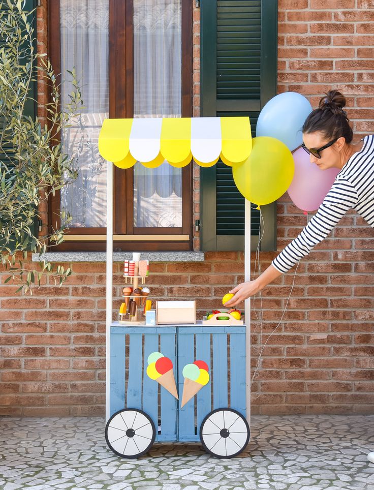 a woman reaching for some balloons on top of a cart