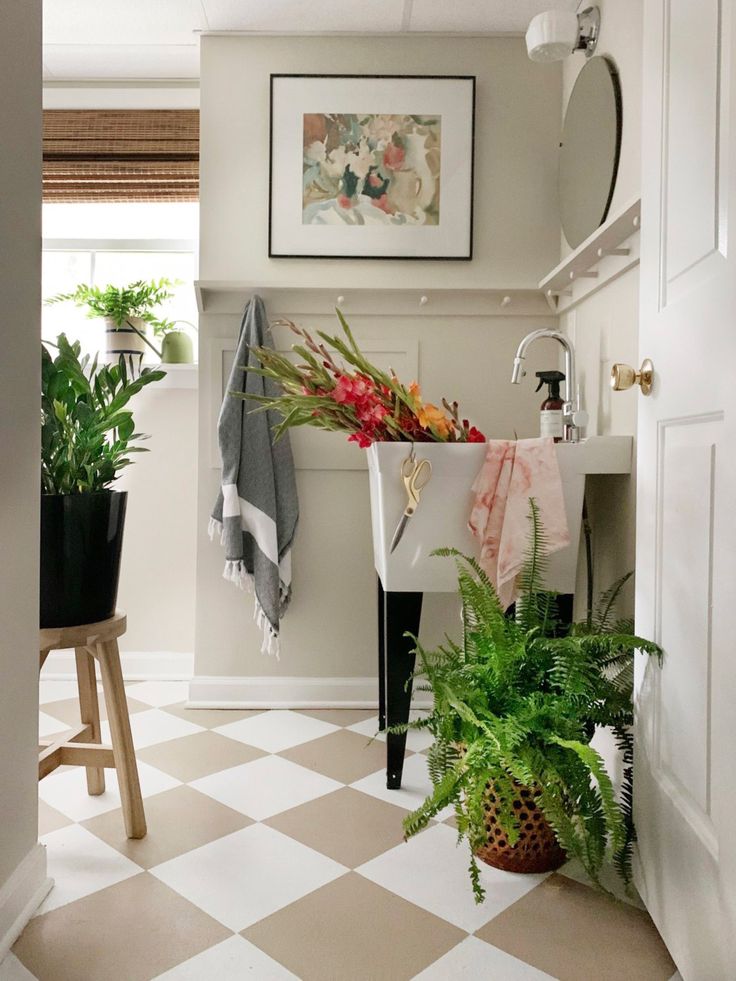 a bathroom with a checkered floor and potted plants on the sink counter next to it