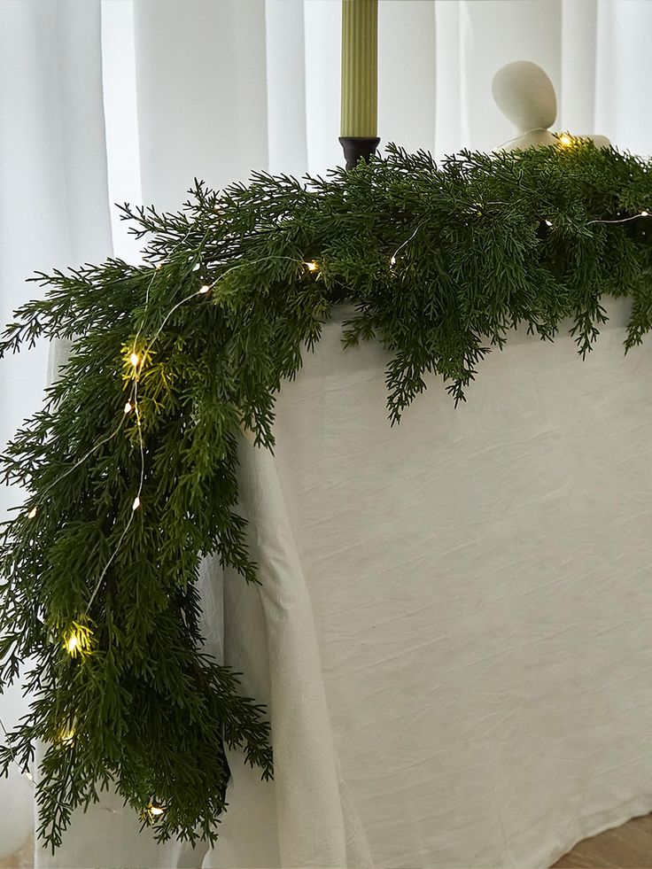 a christmas garland with lights hanging from it's sides on a table in front of a window