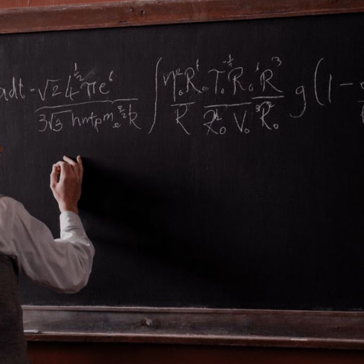 a man writing on a blackboard with chalk