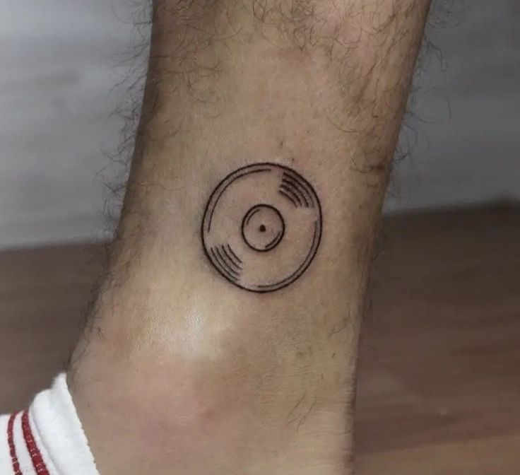 a small tattoo on the foot of a man with a record player disc in it