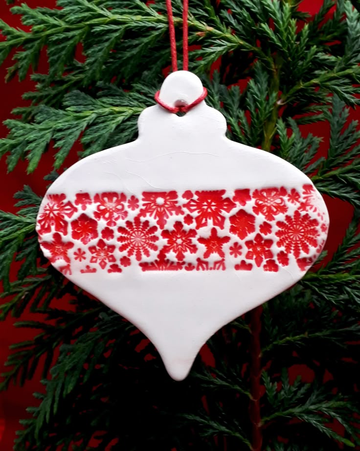 a red and white ornament hanging from a christmas tree