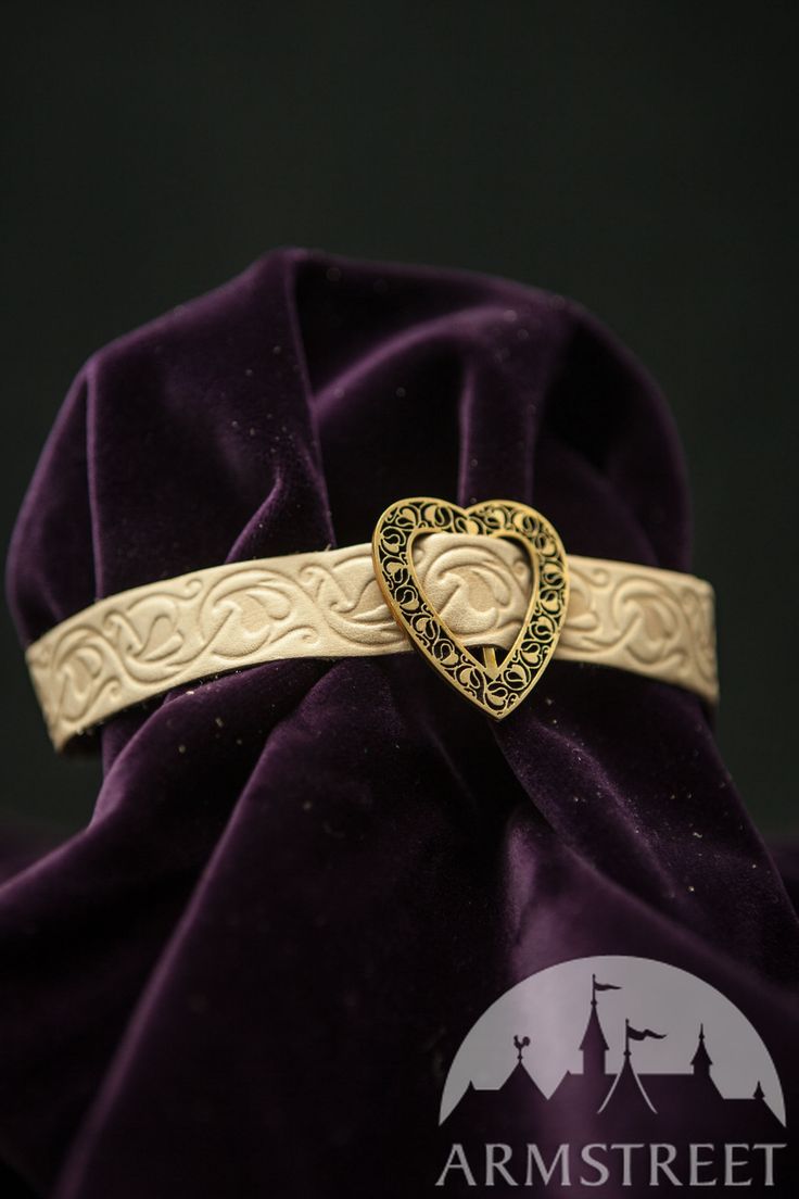 a purple velvet bag with a gold heart shaped brooch on it's side