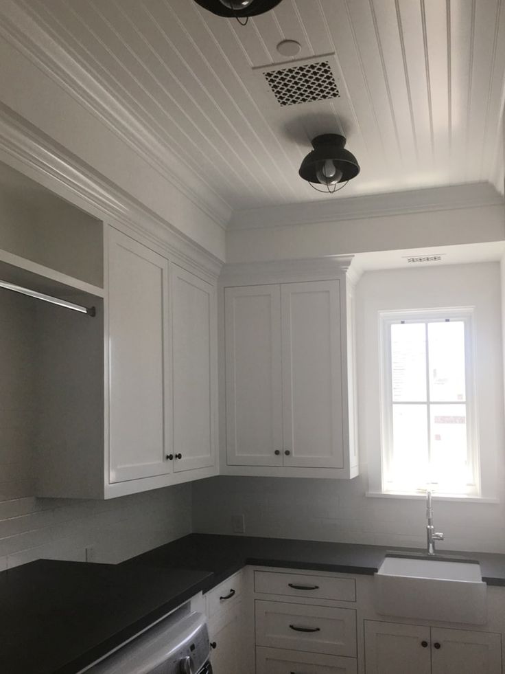 an empty kitchen with white cabinets and black counter tops, including a dishwasher