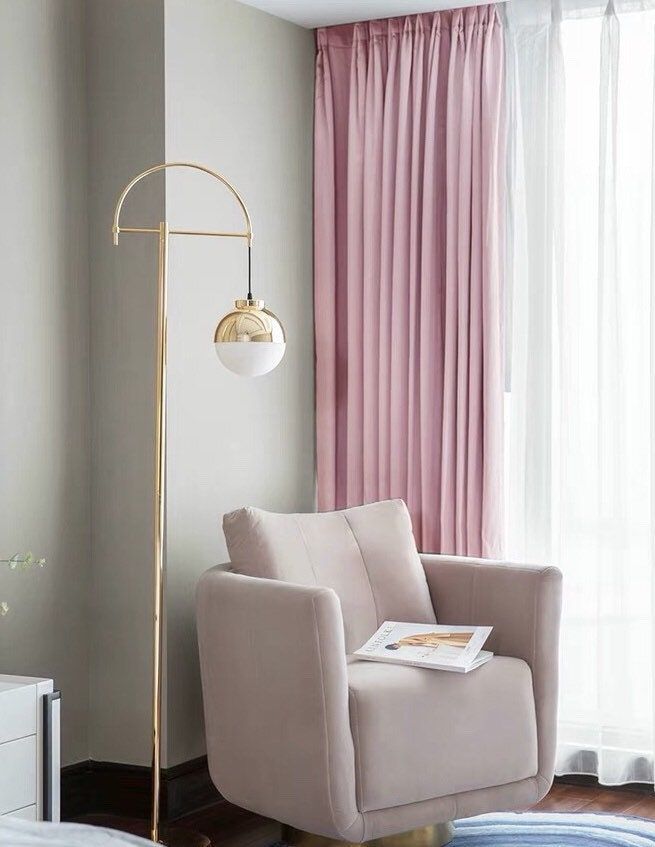 a living room with pink curtains and a gold floor lamp