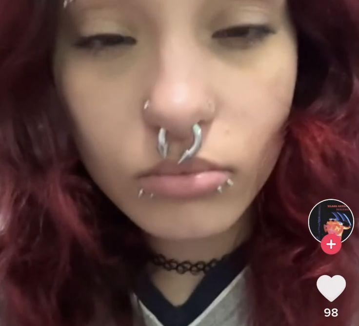 a woman with red hair and piercings on her nose