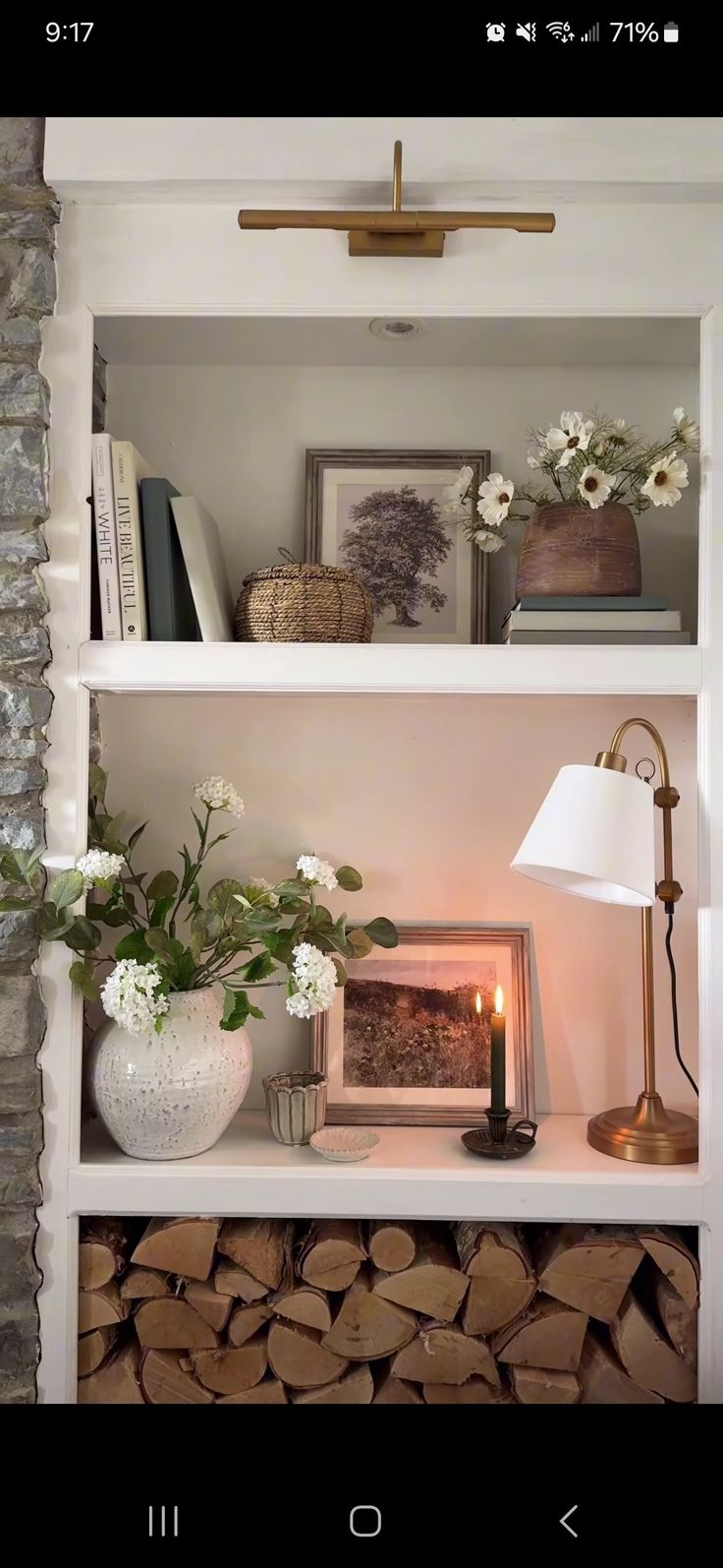 a shelf filled with books and flowers next to a lamp