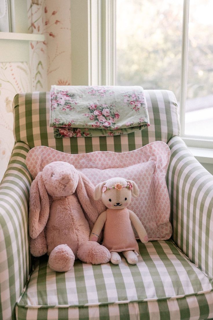 two stuffed animals sitting on a chair in front of a window with pink and green gingham