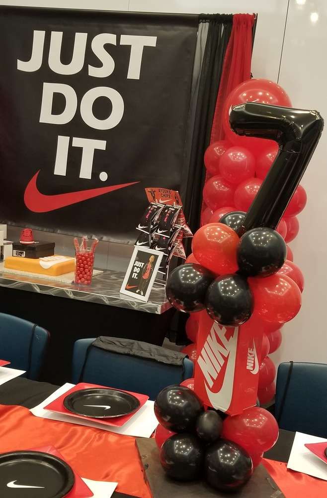 the balloon arch is decorated with black, red and white balloons that read just do it