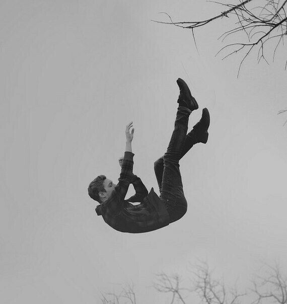 a man flying through the air on top of a snow covered ground next to trees