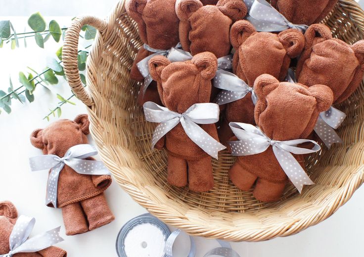 a basket filled with brown teddy bears sitting on top of a table next to plates and utensils