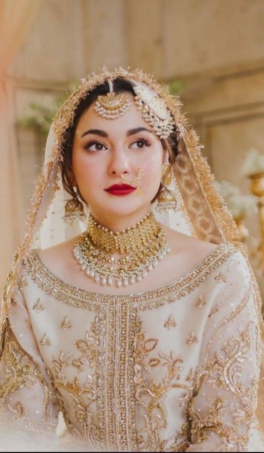 a woman in a wedding dress with jewelry on her head and veil over her face